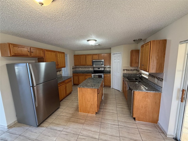 kitchen with decorative backsplash, appliances with stainless steel finishes, a textured ceiling, sink, and a center island