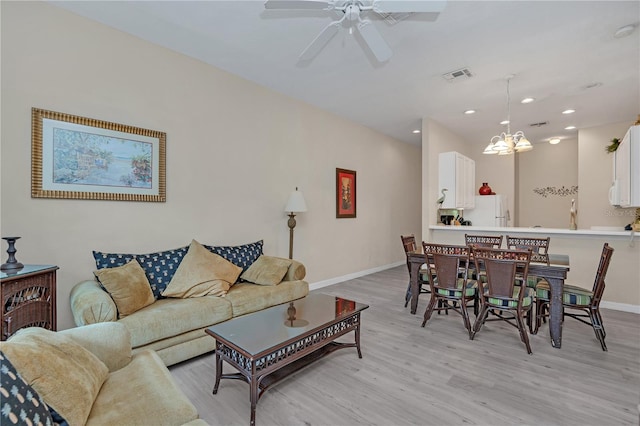 living room featuring ceiling fan with notable chandelier and light hardwood / wood-style flooring