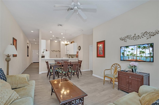 living room featuring light wood-type flooring and ceiling fan with notable chandelier