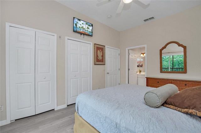 bedroom with ensuite bath, ceiling fan, multiple closets, and light hardwood / wood-style flooring