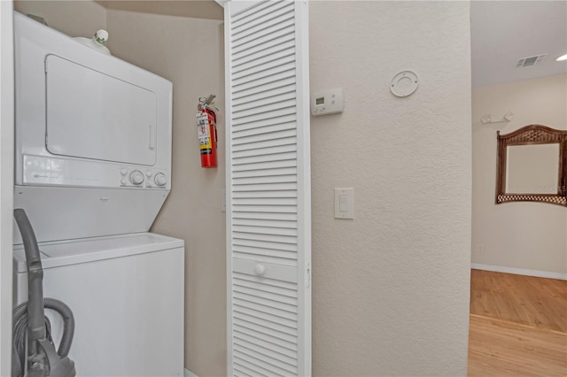 laundry area featuring stacked washer / dryer and light wood-type flooring