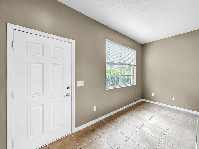 empty room featuring a textured ceiling and light tile patterned floors