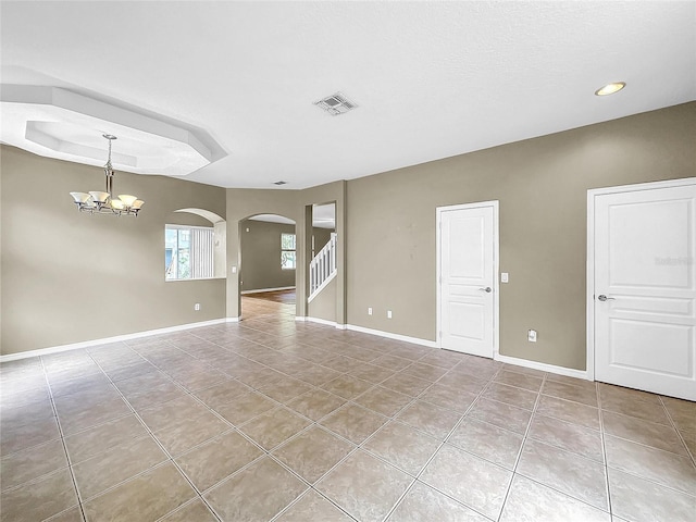 empty room with light tile patterned floors and a notable chandelier