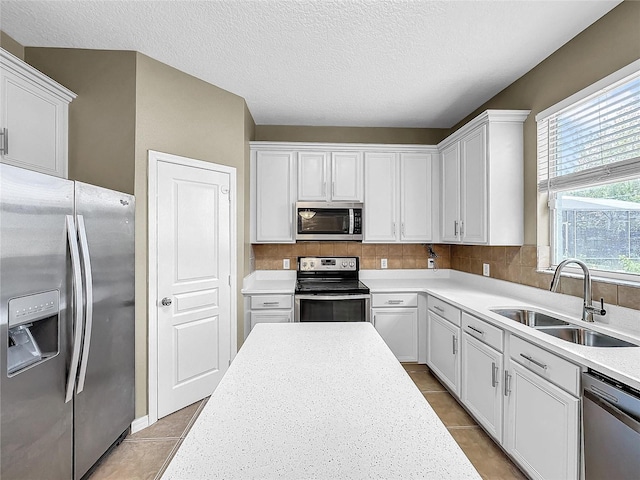 kitchen with white cabinets, a textured ceiling, stainless steel appliances, and sink