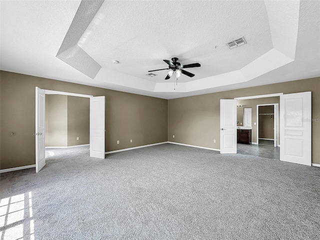 carpeted empty room featuring a textured ceiling, a tray ceiling, and ceiling fan