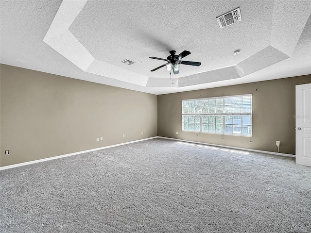 carpeted empty room featuring a tray ceiling, ceiling fan, and a textured ceiling