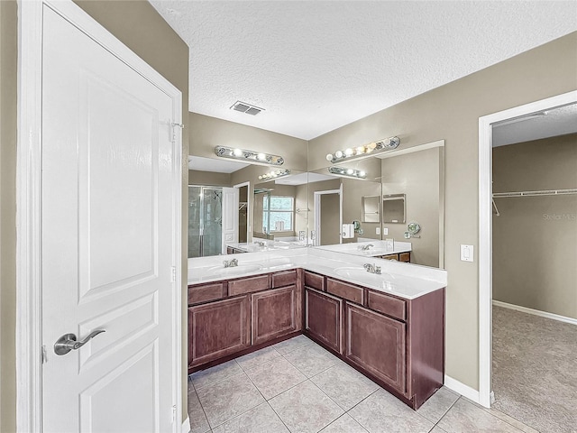 bathroom featuring tile patterned floors, a textured ceiling, walk in shower, and vanity