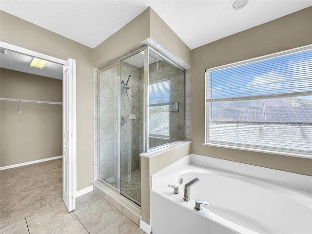 bathroom with a textured ceiling, tile patterned flooring, and plus walk in shower