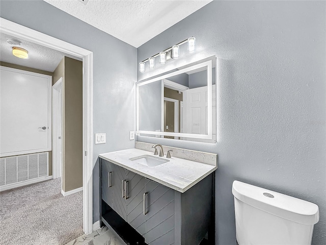 bathroom featuring vanity, toilet, and a textured ceiling