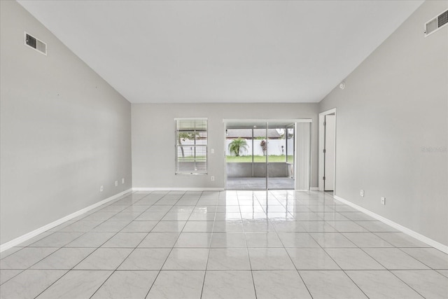 tiled spare room with vaulted ceiling