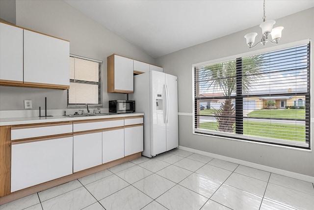 kitchen featuring lofted ceiling, hanging light fixtures, white cabinetry, white refrigerator with ice dispenser, and a notable chandelier