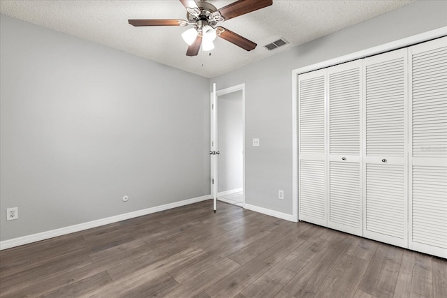 unfurnished bedroom featuring ceiling fan, a textured ceiling, a closet, and wood-type flooring