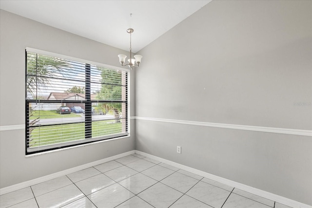 tiled empty room featuring vaulted ceiling and a chandelier