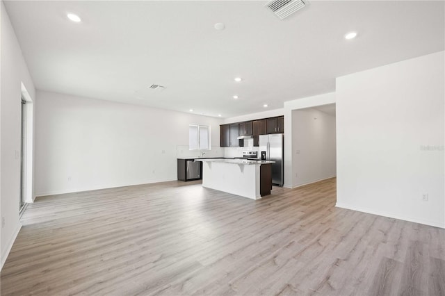 kitchen with a center island, a kitchen bar, light hardwood / wood-style flooring, dark brown cabinetry, and stainless steel fridge with ice dispenser