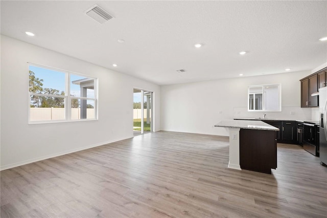 kitchen featuring light stone counters, light hardwood / wood-style floors, a center island, and a breakfast bar