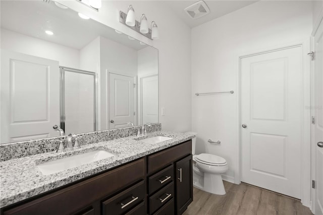 bathroom featuring a shower with door, wood-type flooring, vanity, and toilet