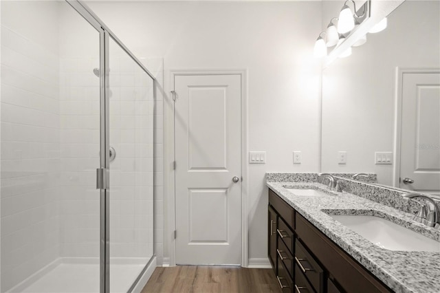 bathroom with wood-type flooring, a shower with shower door, and vanity