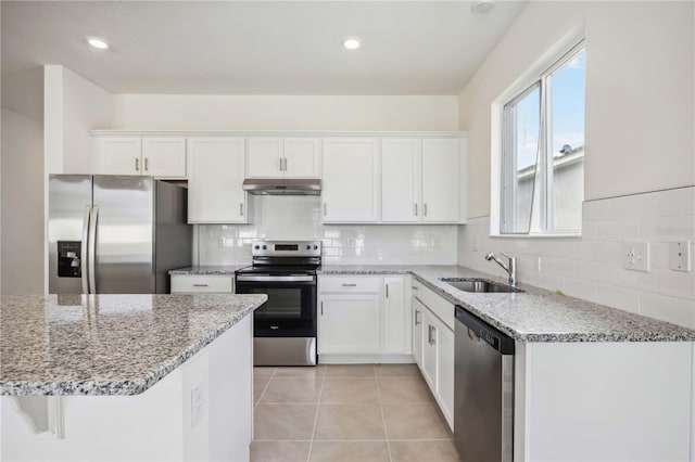 kitchen featuring appliances with stainless steel finishes, light tile patterned flooring, white cabinets, light stone counters, and sink