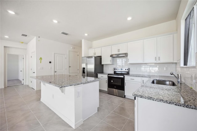 kitchen with a kitchen island, sink, light tile patterned floors, stainless steel appliances, and white cabinets