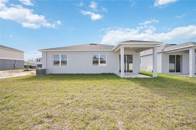 back of property with a yard and central AC