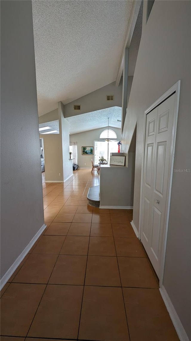 corridor featuring a textured ceiling, tile patterned flooring, lofted ceiling with beams, and a chandelier