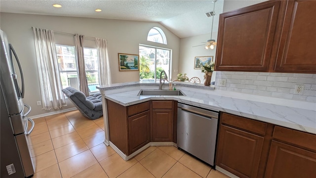 kitchen featuring appliances with stainless steel finishes, vaulted ceiling, kitchen peninsula, a textured ceiling, and sink