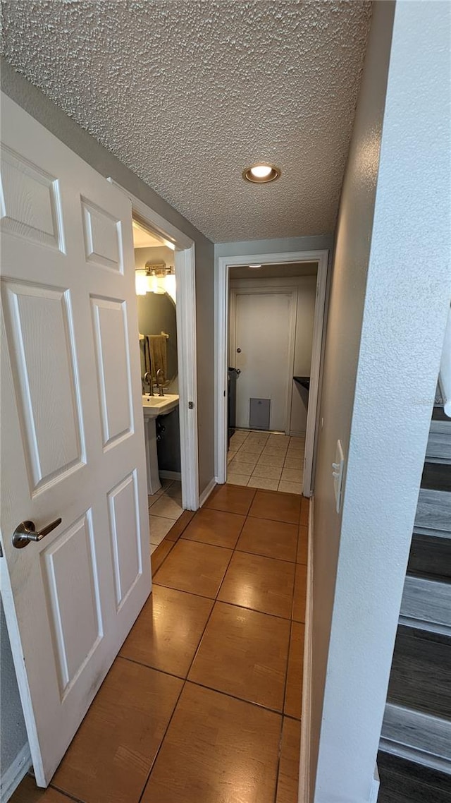 corridor featuring a textured ceiling and tile patterned floors