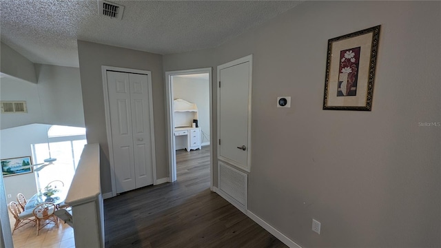 corridor with a textured ceiling and dark hardwood / wood-style flooring