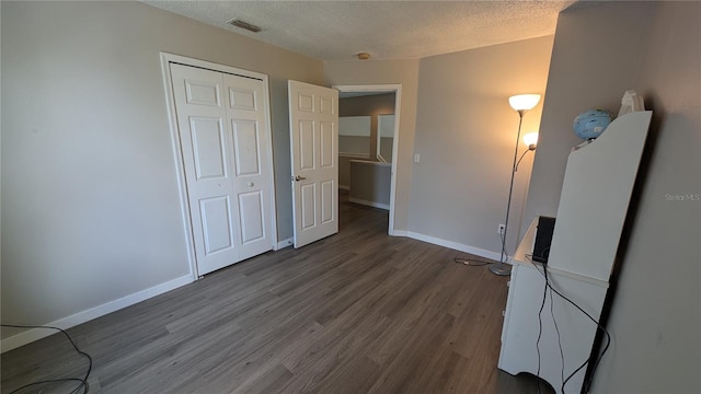 unfurnished bedroom with a textured ceiling, a closet, and hardwood / wood-style floors