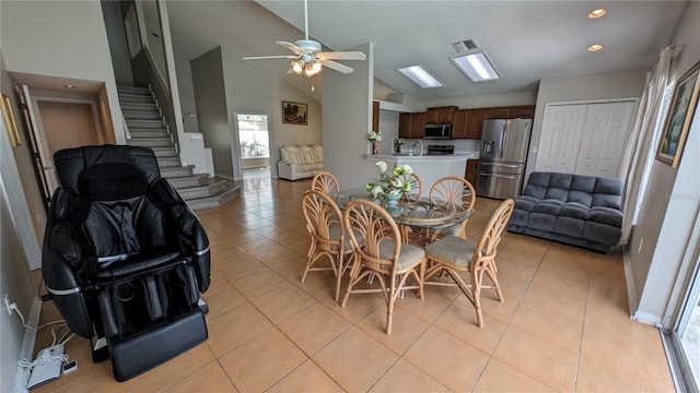 dining room featuring ceiling fan, light tile patterned flooring, sink, and high vaulted ceiling