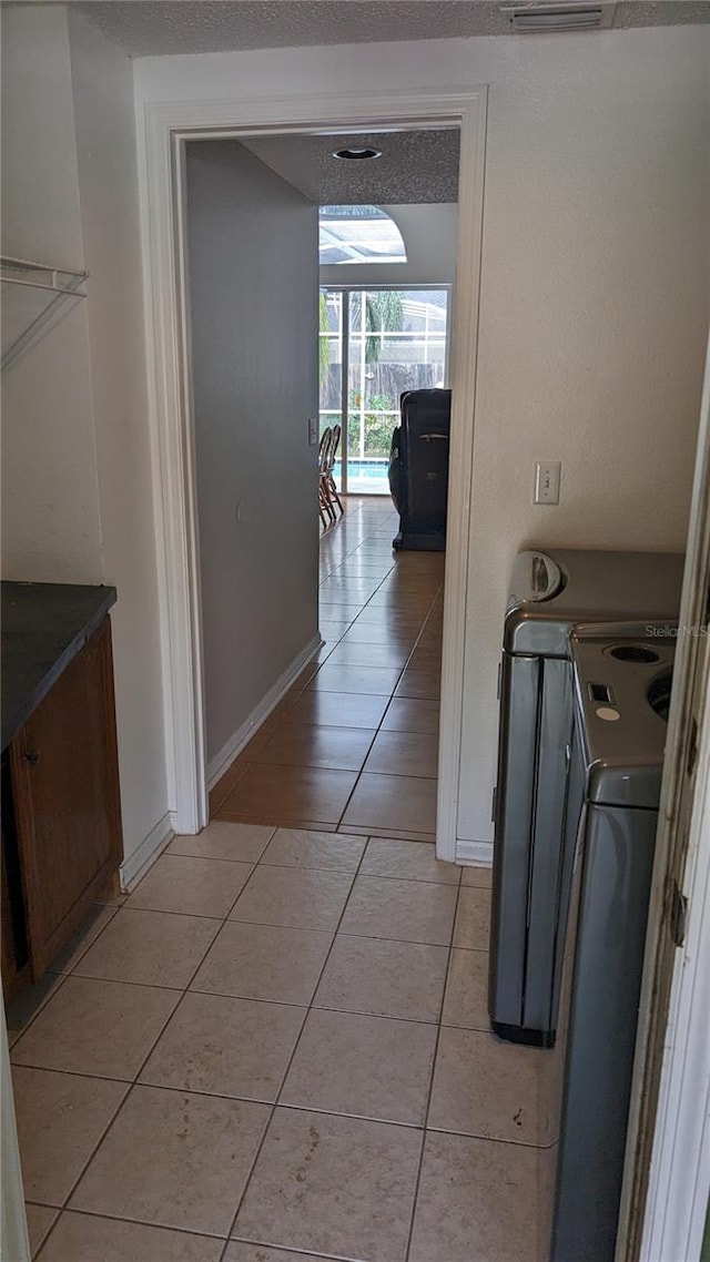 hall featuring washer / dryer, a textured ceiling, and light tile patterned flooring