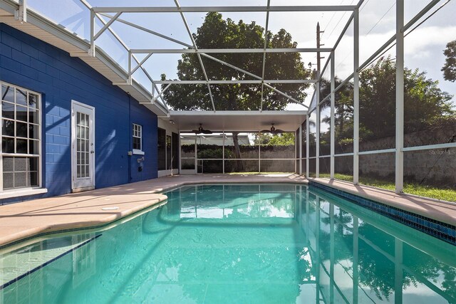 view of swimming pool with a patio, glass enclosure, and ceiling fan