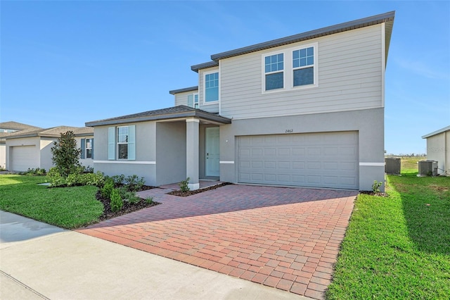 view of front of property featuring a front yard, a garage, and central AC unit