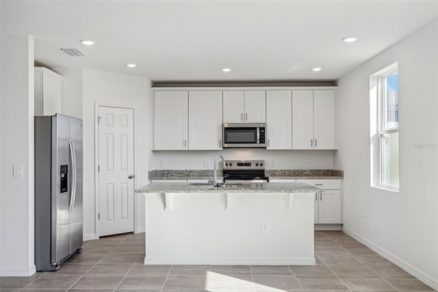 kitchen featuring a wealth of natural light, appliances with stainless steel finishes, and an island with sink