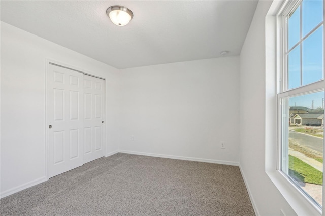 unfurnished bedroom with a closet, multiple windows, and carpet floors