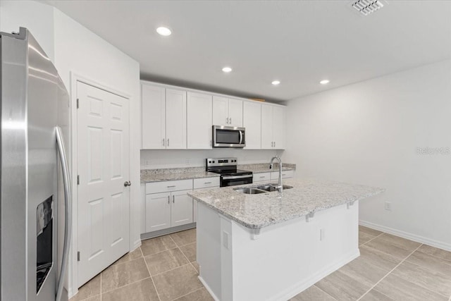 kitchen featuring sink, stainless steel appliances, light stone countertops, an island with sink, and white cabinetry