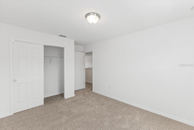 unfurnished bedroom featuring a closet and light carpet