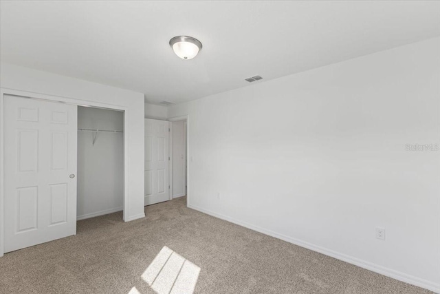 unfurnished bedroom featuring a closet and light colored carpet