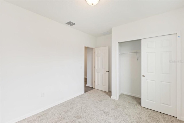 unfurnished bedroom featuring light colored carpet and a closet