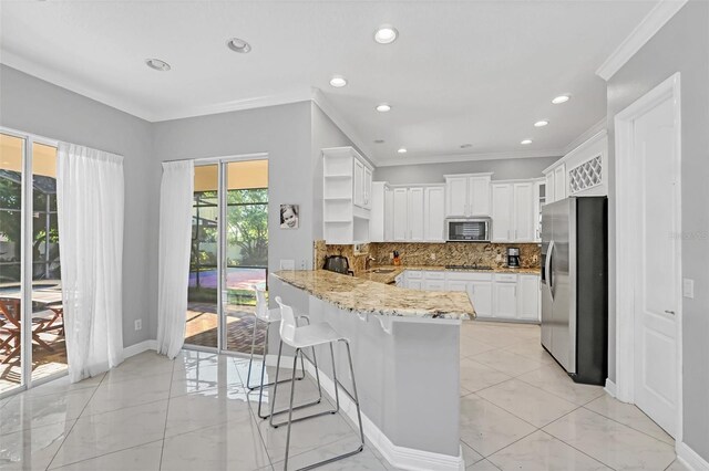 kitchen with stainless steel appliances, kitchen peninsula, backsplash, white cabinets, and ornamental molding