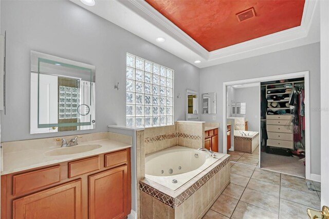 bathroom with tile patterned flooring, crown molding, a raised ceiling, tiled bath, and vanity