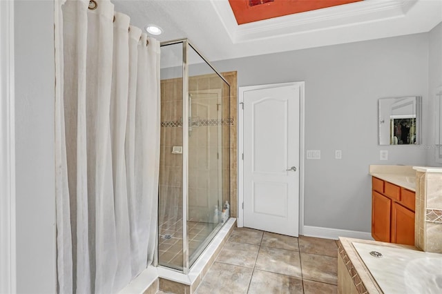 bathroom with tile patterned floors, a tray ceiling, walk in shower, and vanity