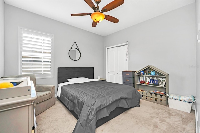 carpeted bedroom with ceiling fan and a closet