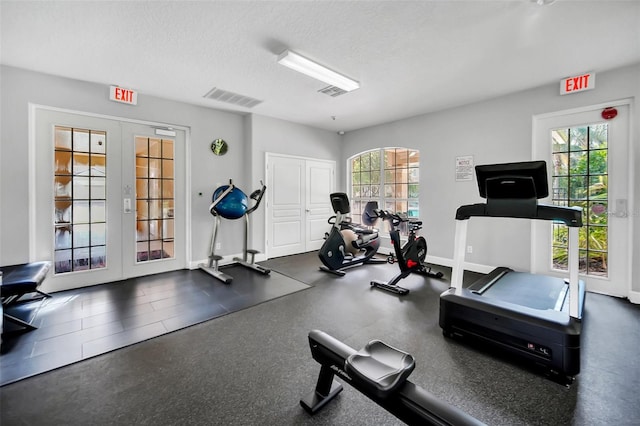 exercise room with french doors, a wealth of natural light, and a textured ceiling