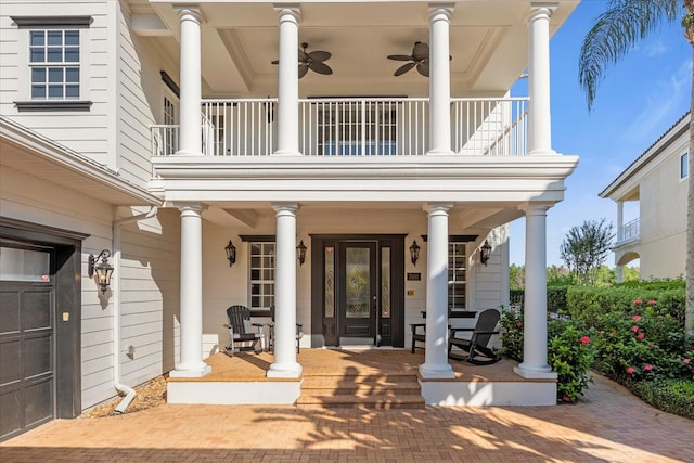 view of exterior entry with a balcony, ceiling fan, and covered porch