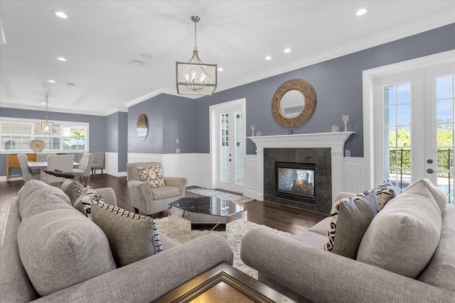 living room with an inviting chandelier, crown molding, dark hardwood / wood-style flooring, and a premium fireplace