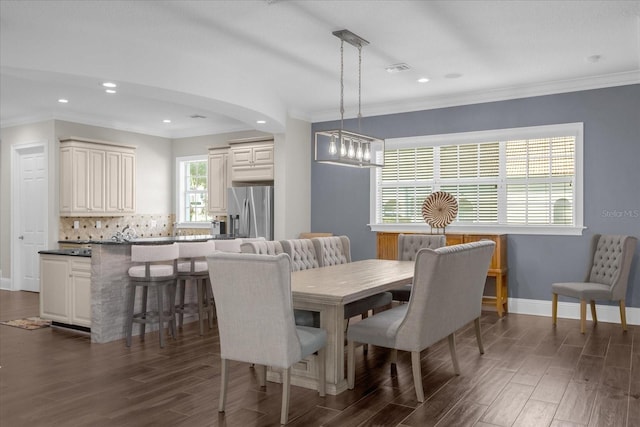 dining space featuring crown molding, dark wood-type flooring, and a chandelier