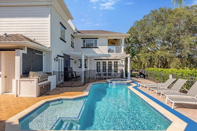 view of swimming pool featuring an in ground hot tub, area for grilling, a patio area, and exterior kitchen