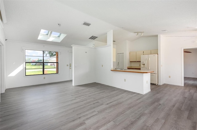 unfurnished living room with light hardwood / wood-style flooring, vaulted ceiling with skylight, and a textured ceiling