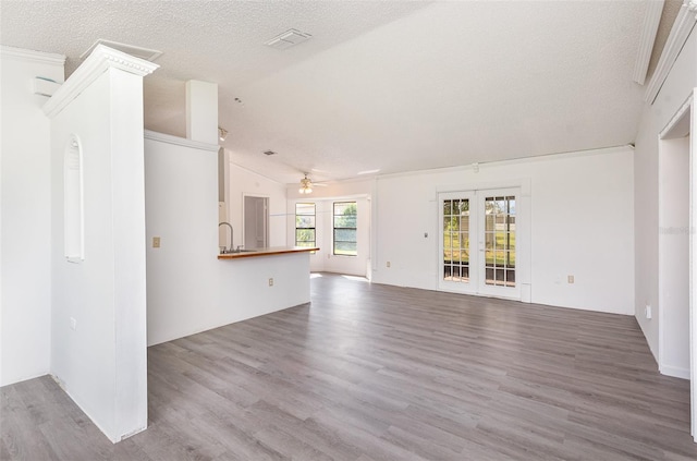 unfurnished living room with vaulted ceiling, ceiling fan, hardwood / wood-style flooring, and a textured ceiling